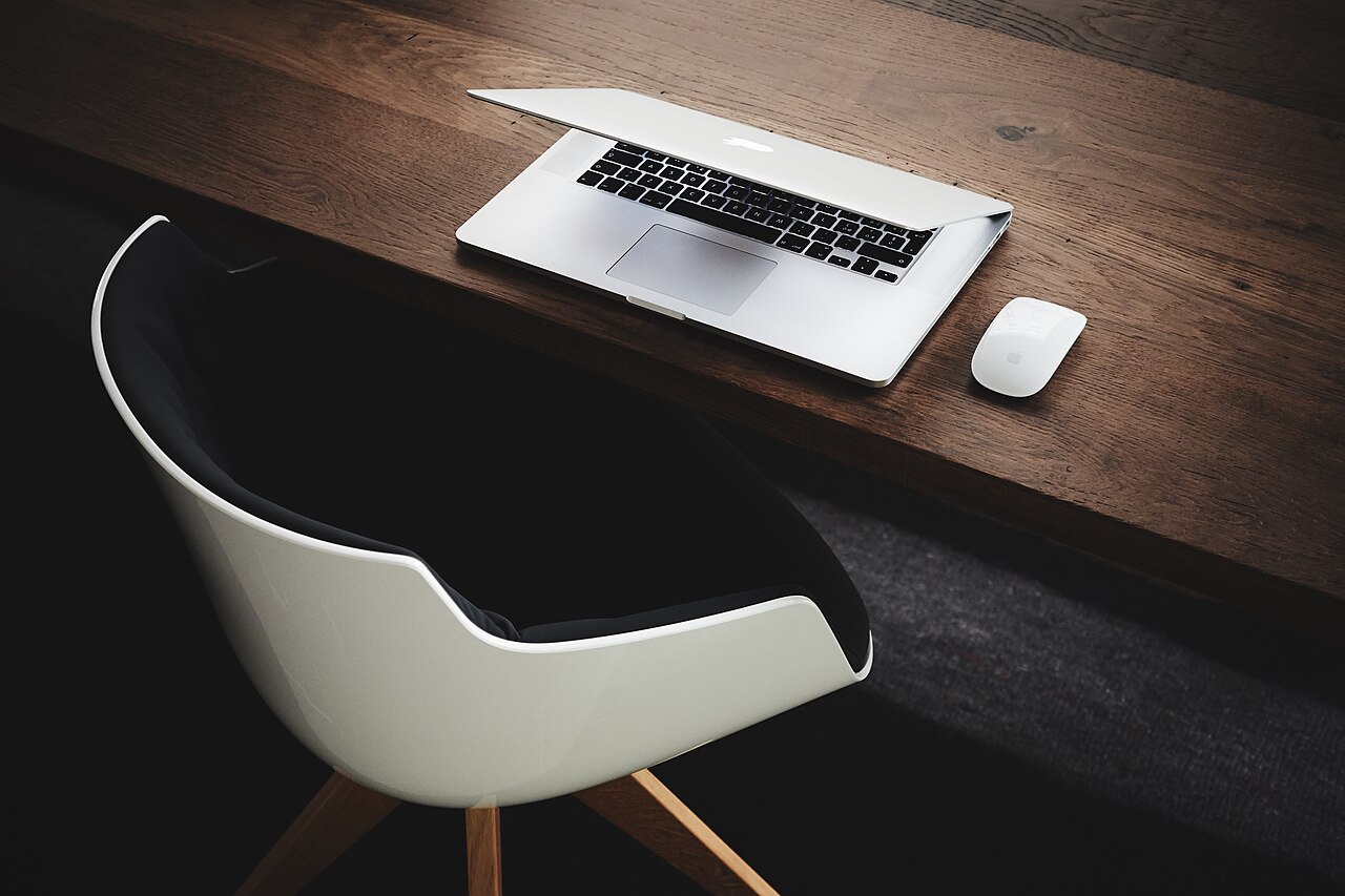 A cleared office desk with a closed laptop and an empty chair at the end of a working day